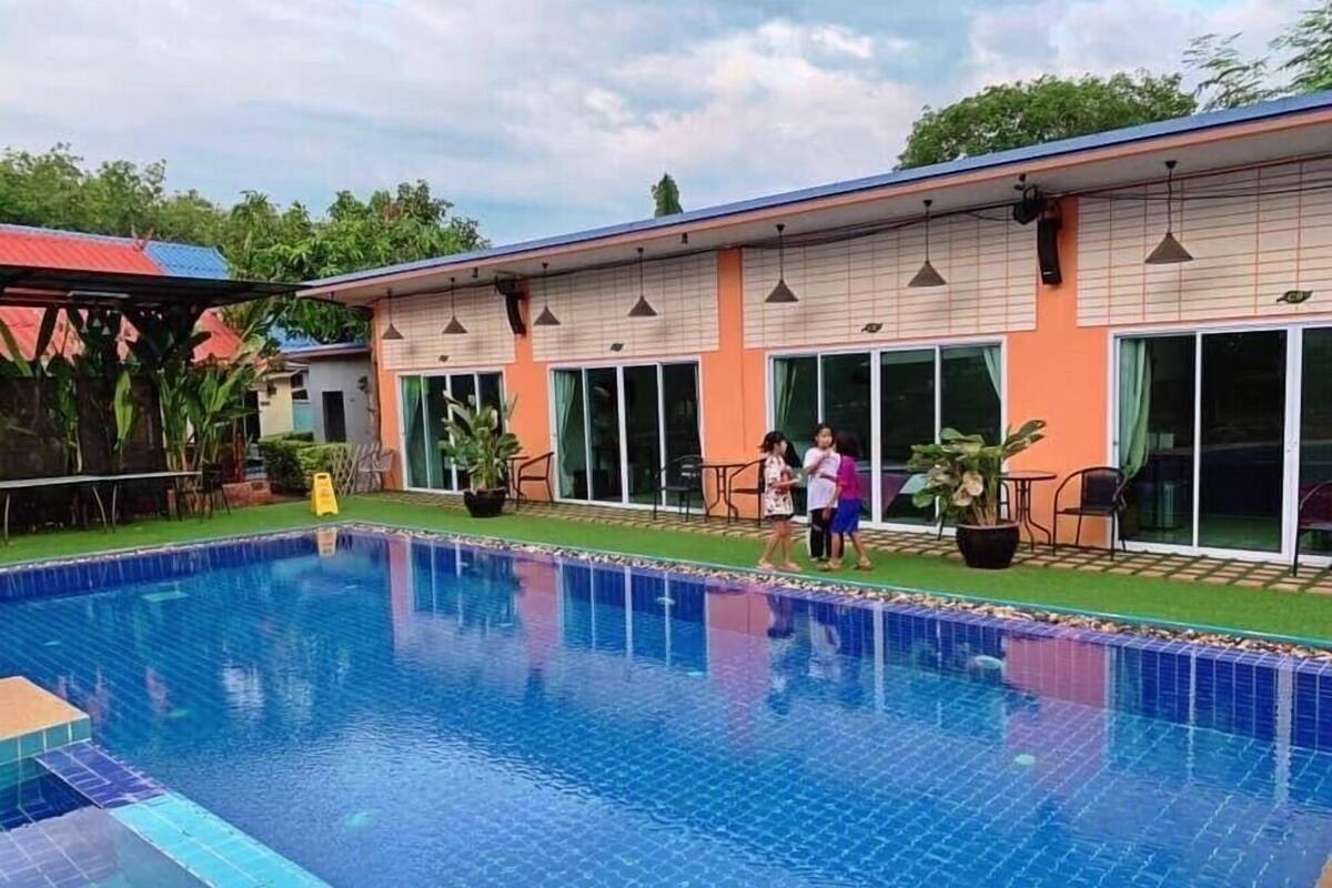 Ein Pool mit Fliesenrand, umgeben von einem Gebäude mit großen Fenstern und einer flachen Dachterrasse.