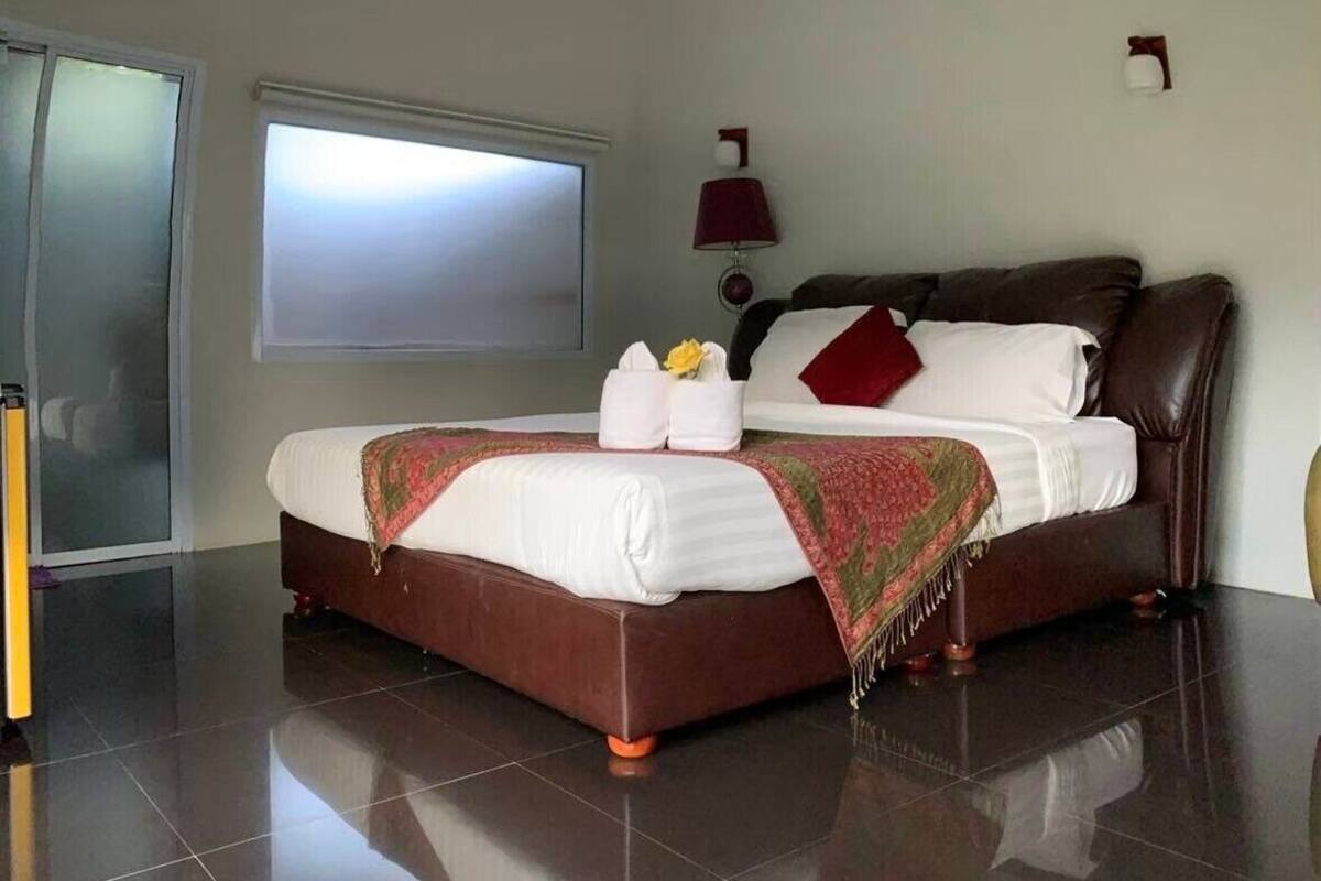 Ein Hotelzimmer mit einem großen Bett, einem Fenster, einer Lampe und einem Spiegel.