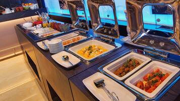 Un buffet con diversos platos, como huevos revueltos, albóndigas y verduras.