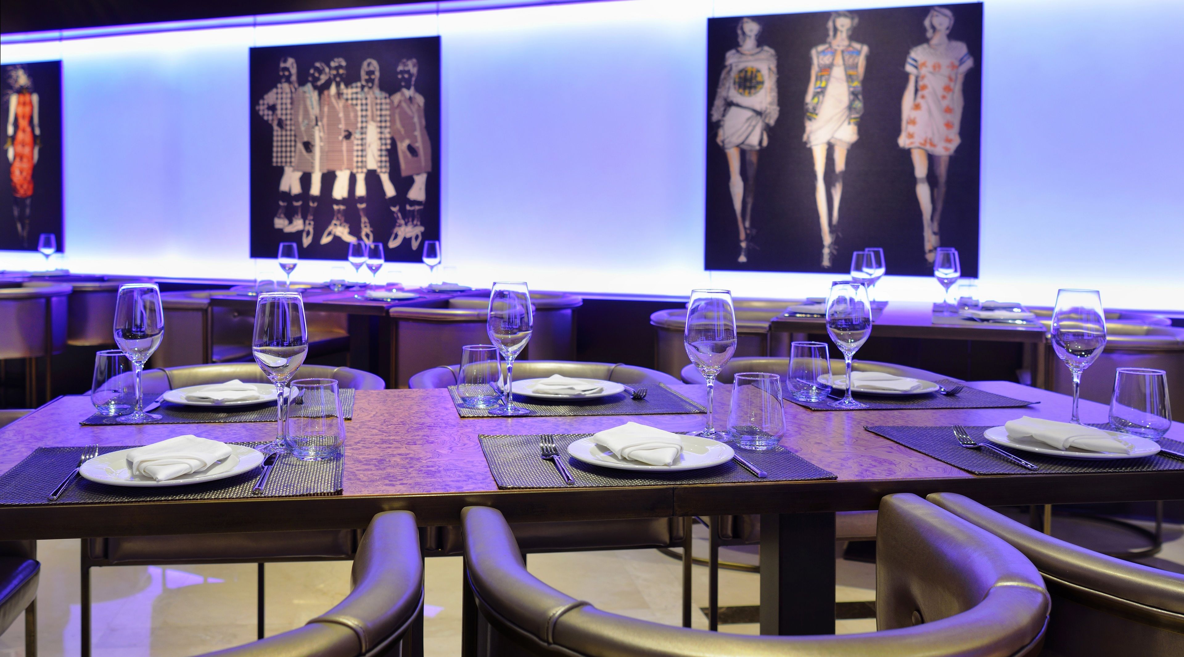A restaurant interior with tables set for dining, featuring a modern design with a blue ambient lighting.