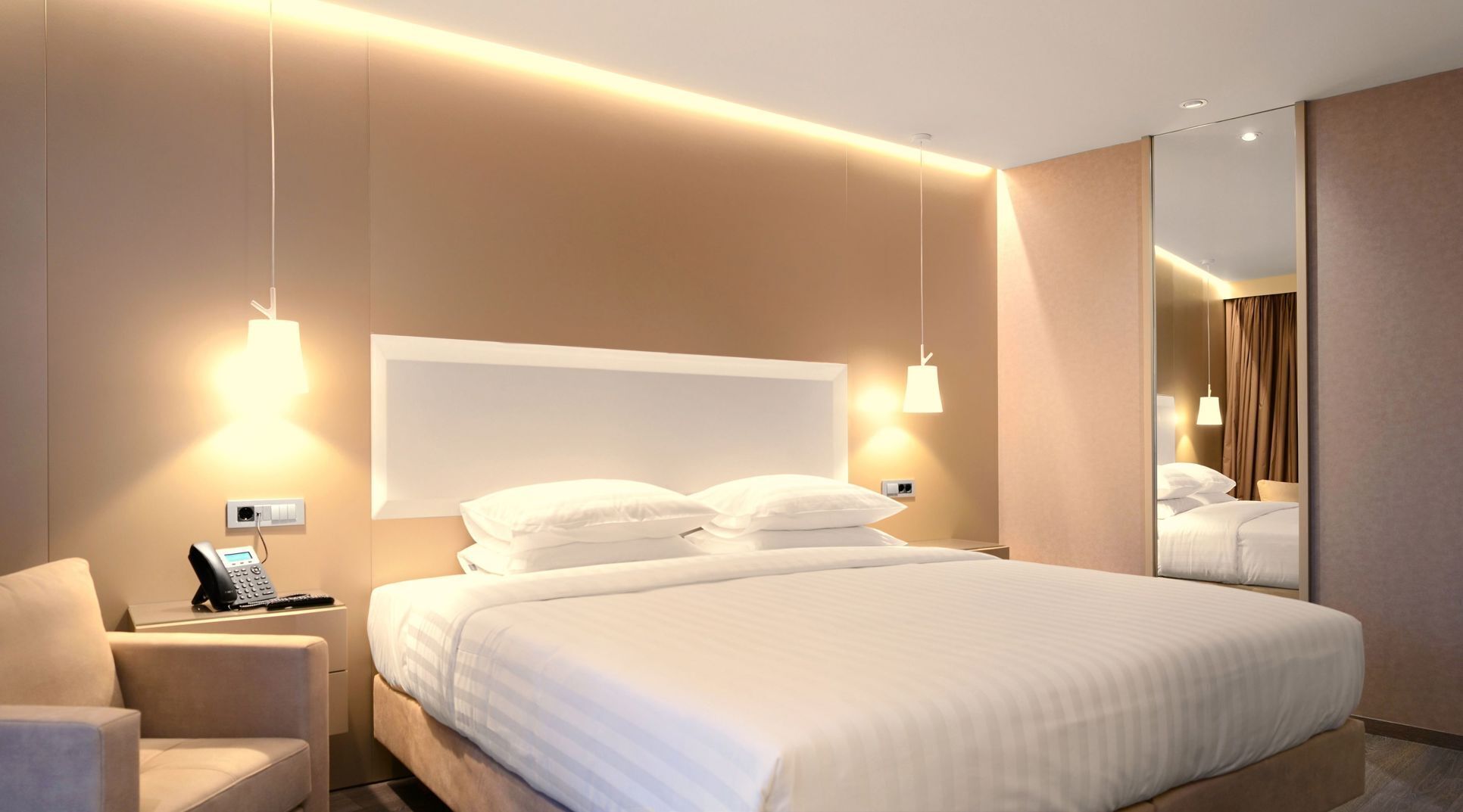A modern hotel room with a large bed, bedside lamps, a telephone, and a mirror.