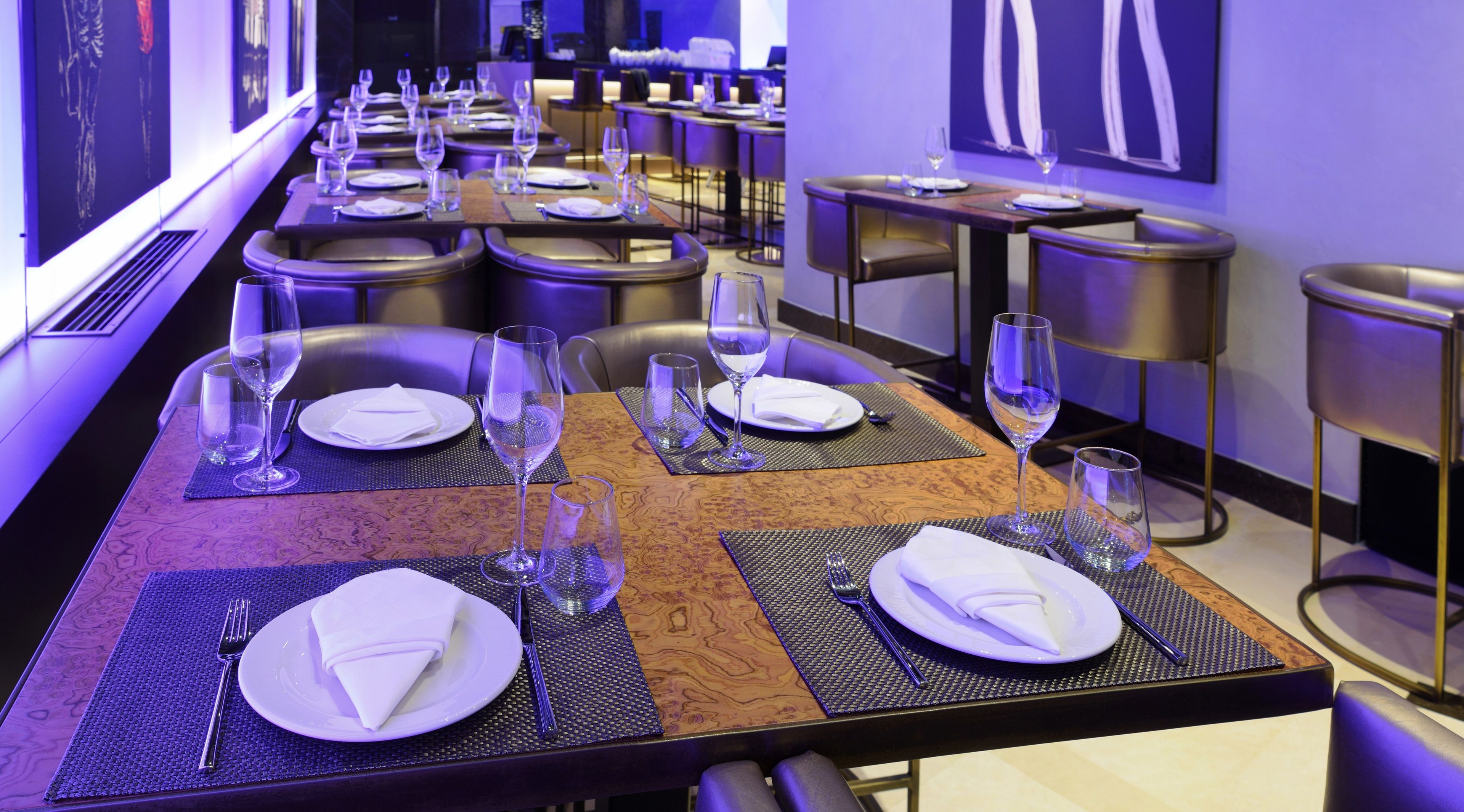 A restaurant with tables set for dining, featuring a modern design with a mix of wood and metal elements.