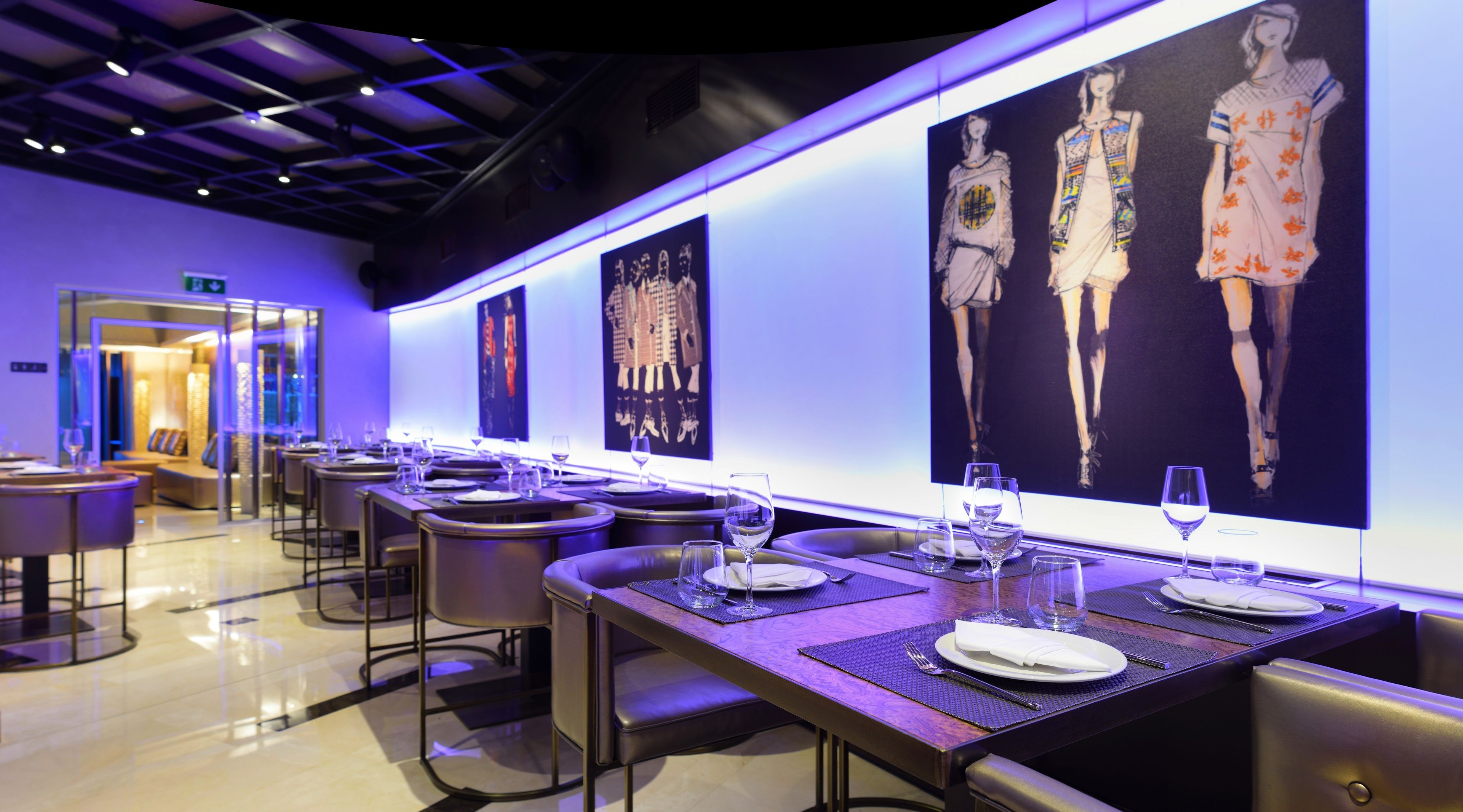 Un restaurante moderno con mesas dispuestas para comer, que presenta obras de arte en las paredes.