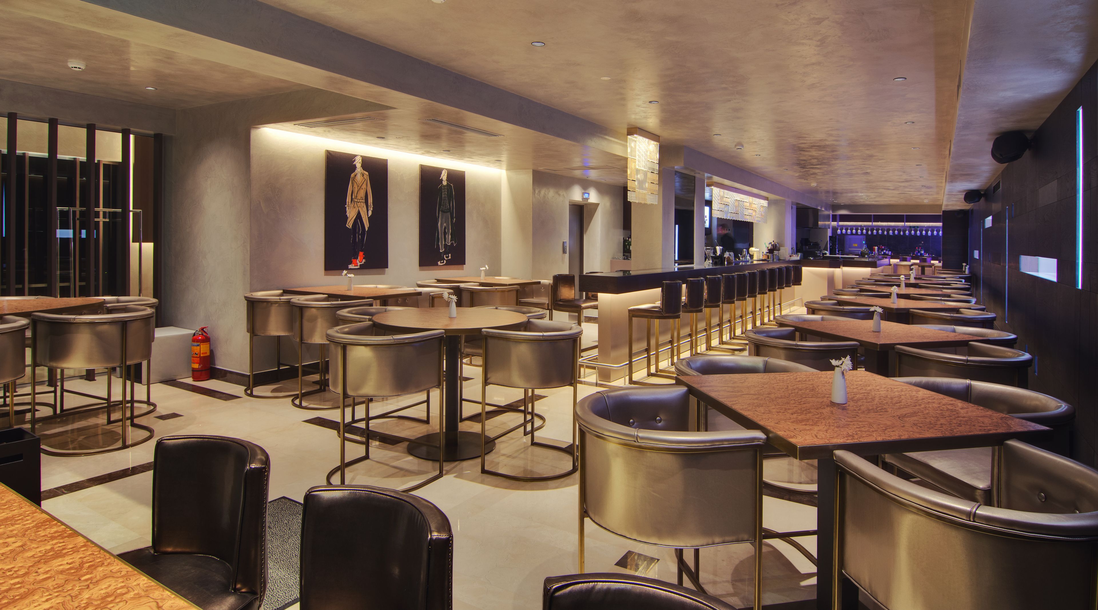 Ein modernes Restaurant mit verschiedenen Sitzbereichen, darunter Barhocker und Tische, sowie einer langen Theke mit Bar.