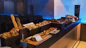 Un buffet proposant une variété de pains, de viennoiseries et un assortiment de fruits.