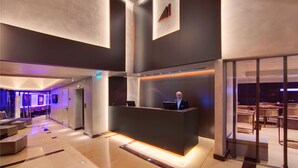 Un hall d’hôtel moderne comprenant un comptoir d’accueil, un espace salon et une cloison en verre qui sépare le hall de la salle à manger.