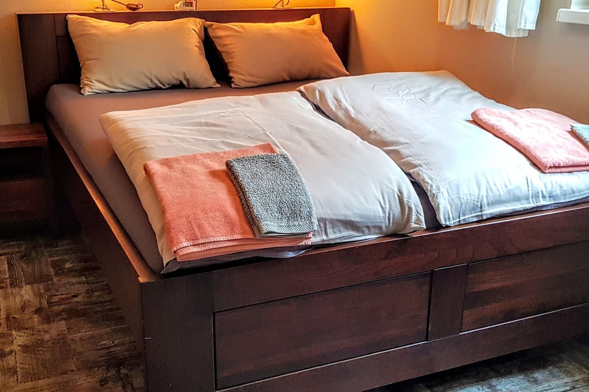 A neatly made bed with pillows and folded towels.