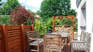 A wooden deck with a table and chairs, surrounded by a wooden fence and greenery. - Bed & Breakfast Comfort House Olten - Lostorf (Lostorf)
