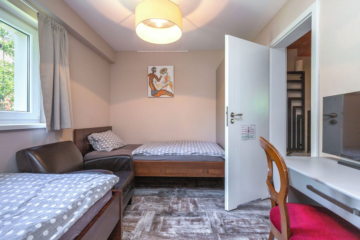 A compact room with two beds, a desk, and a chair.