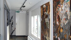 A hallway with artwork on the walls, a door with an exit sign, and a radiator under a window. - Bed & Breakfast Comfort House Olten - Lostorf (Lostorf)