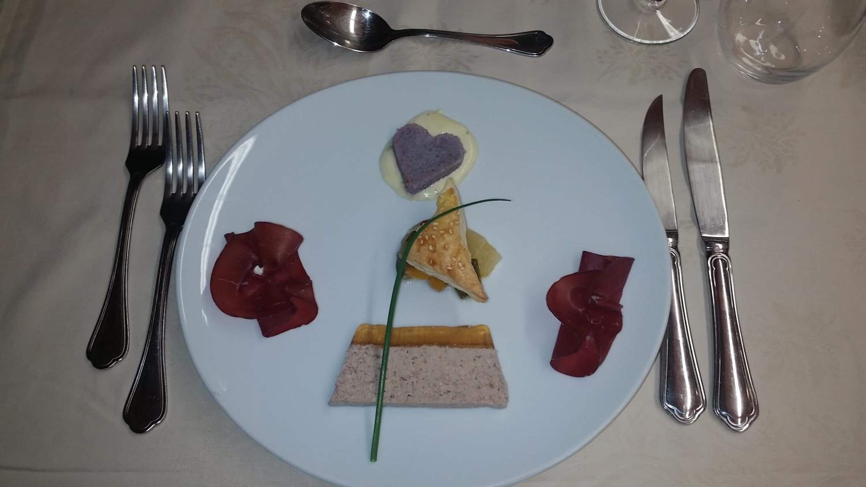 Une assiette contenant des aliments et des couverts, posée sur une table.