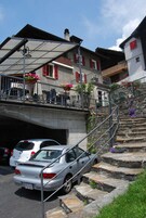 Un edificio con una escalera de piedra que lleva a un balcón con contraventanas rojas.