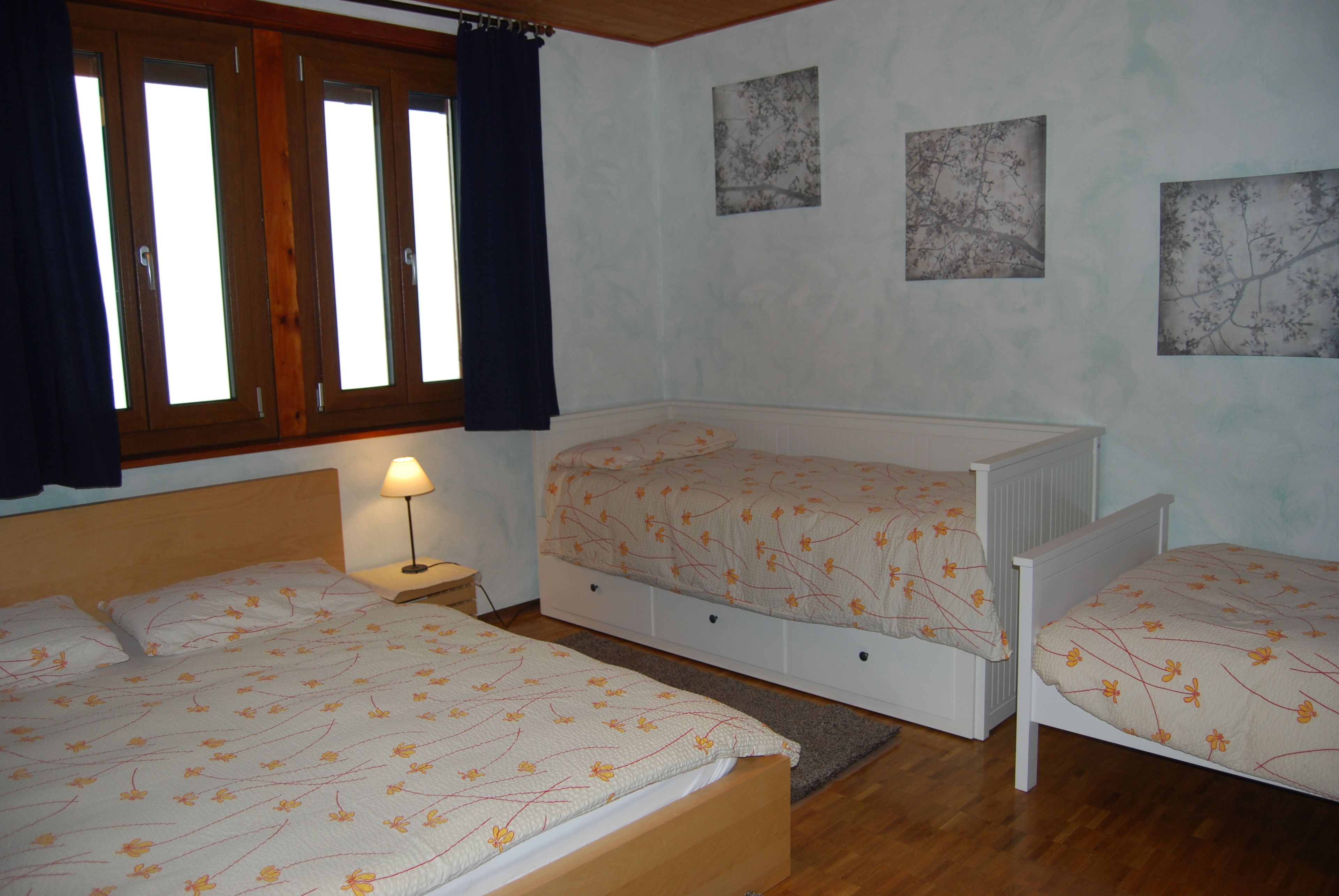 A bedroom with two beds, a nightstand, and a window with curtains.