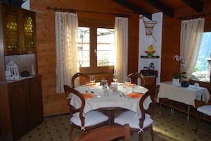 Comedor de madera con una mesa preparada para cuatro, sillas de madera y una ventana con cortinas.