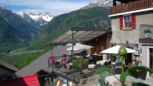 A mountain-view restaurant with outdoor seating and a wooden balcony overlooking a valley. - Osteria Anzonico (Faido)