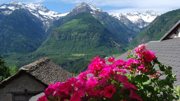 A mountain landscape with snow-capped peaks and lush green valleys. - Osteria Anzonico (Faido)