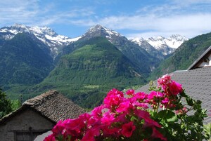 Un paisaje montañoso con picos nevados y valles verdes exuberantes.