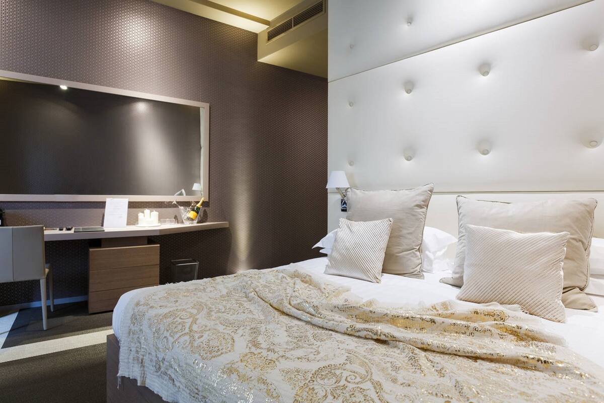 A hotel room with a large bed, a desk with a chair, a flat-screen TV, and a modern headboard.
