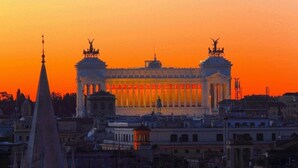 A grand building with two prominent towers and a central section with columns, surrounded by other structures. - Private Luxury Suite (Rome)