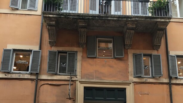 A building with multiple storefronts, including a visible shoe store and a sign advertising a 50% discount. - Private Luxury Suite (Rome)