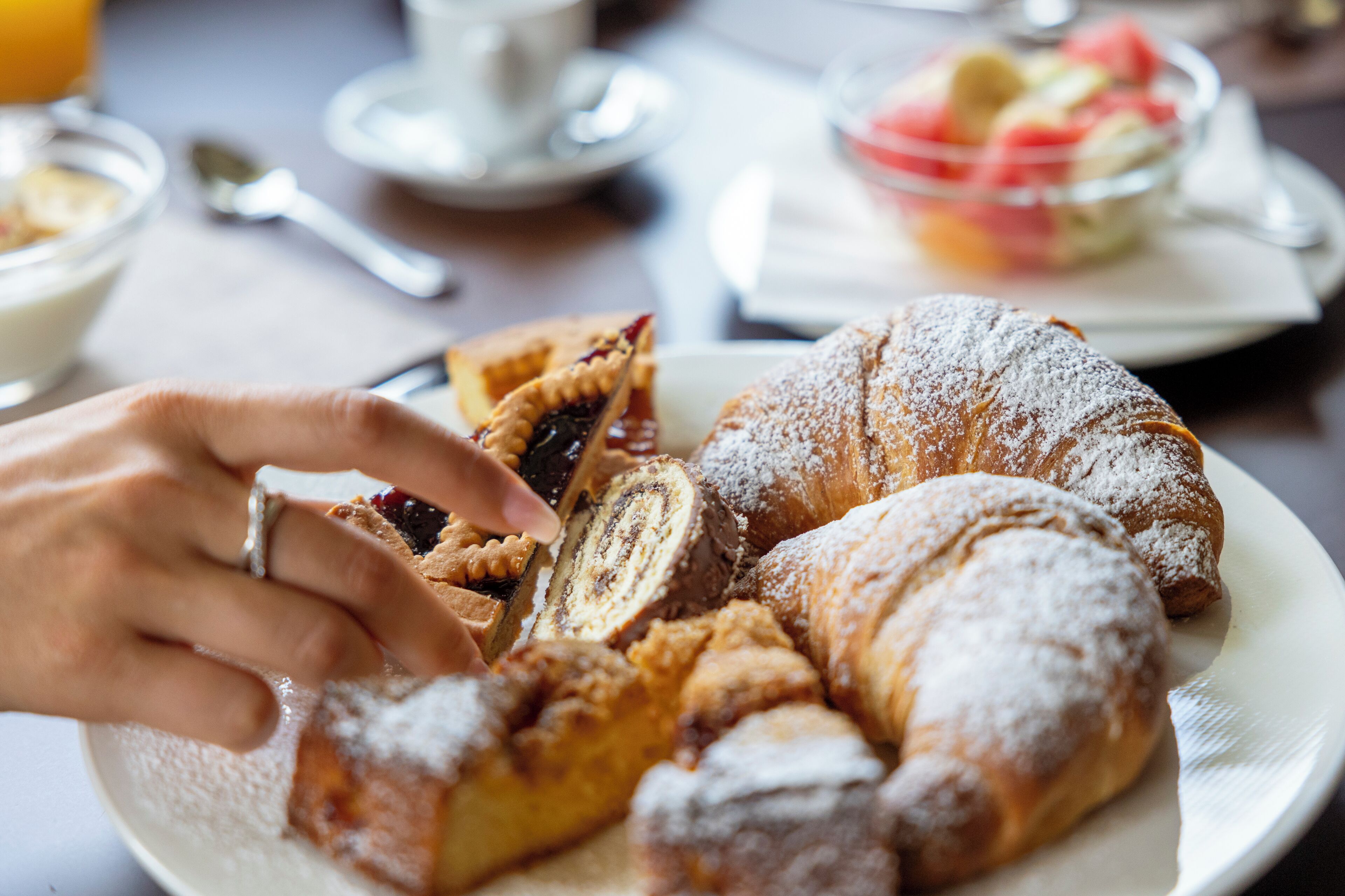 A plate with pastries and a hand reaching for one.