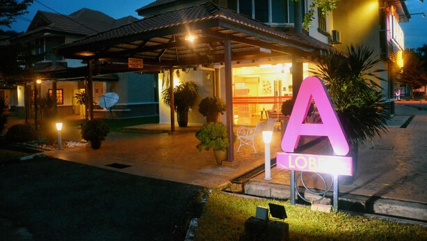 A hotel entrance with a large illuminated 'A' sign, a covered outdoor area with seating, and a well-lit interior. - Kertih Damansara Inn (Kerteh)
