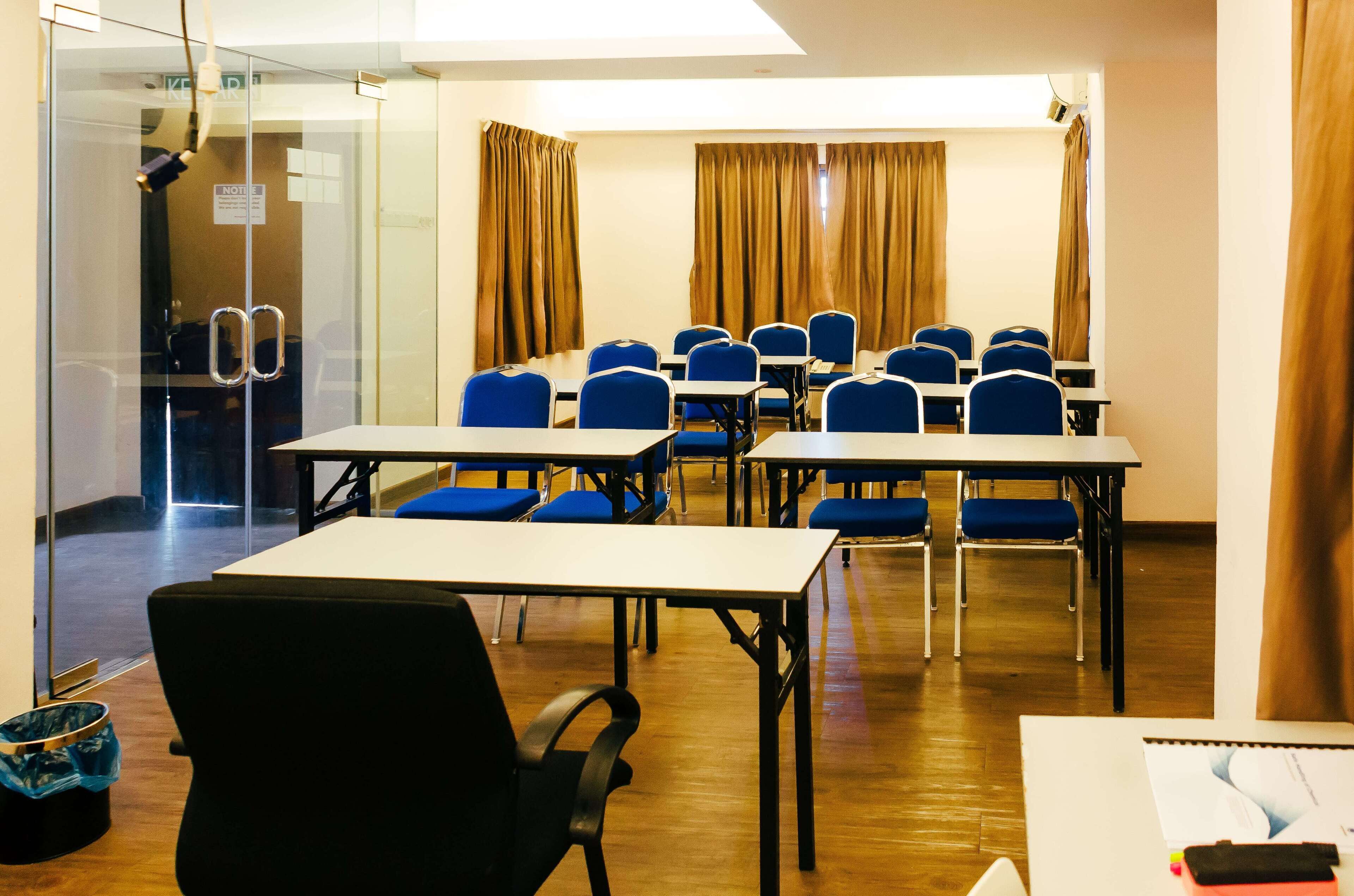 Un salón de conferencias con mesas, sillas, un muro de cristal y cortinas.