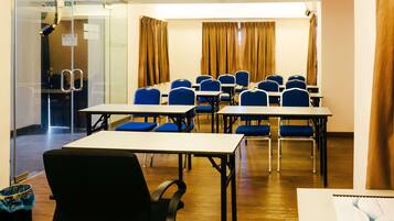 A conference room with tables and chairs, a glass wall, and curtains.