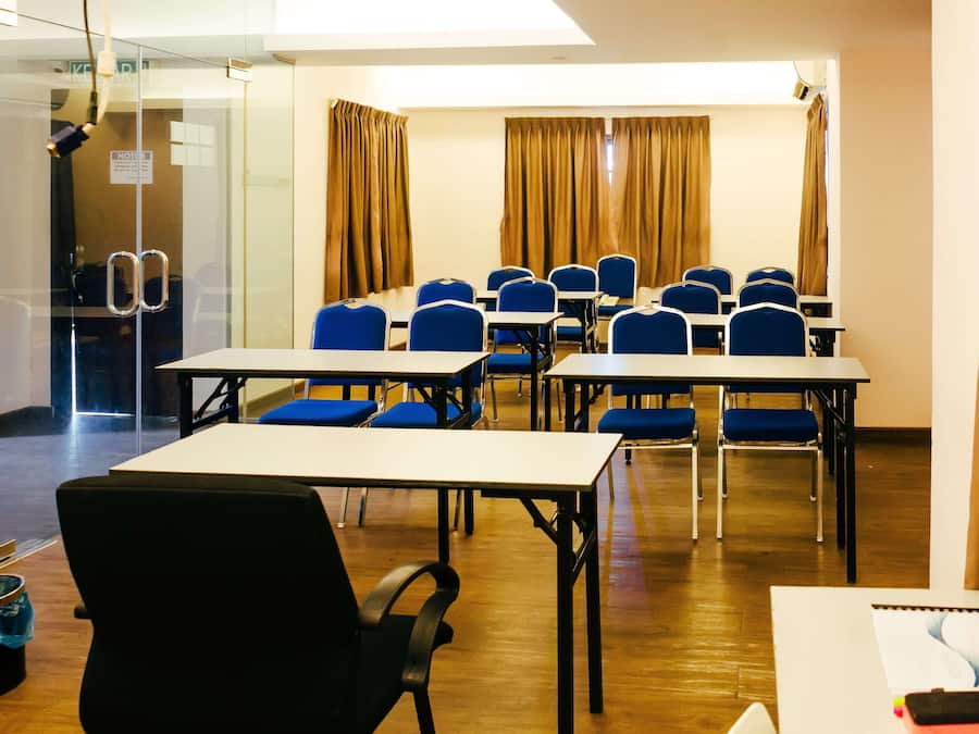 A conference room with tables and chairs, a glass wall, and curtains.