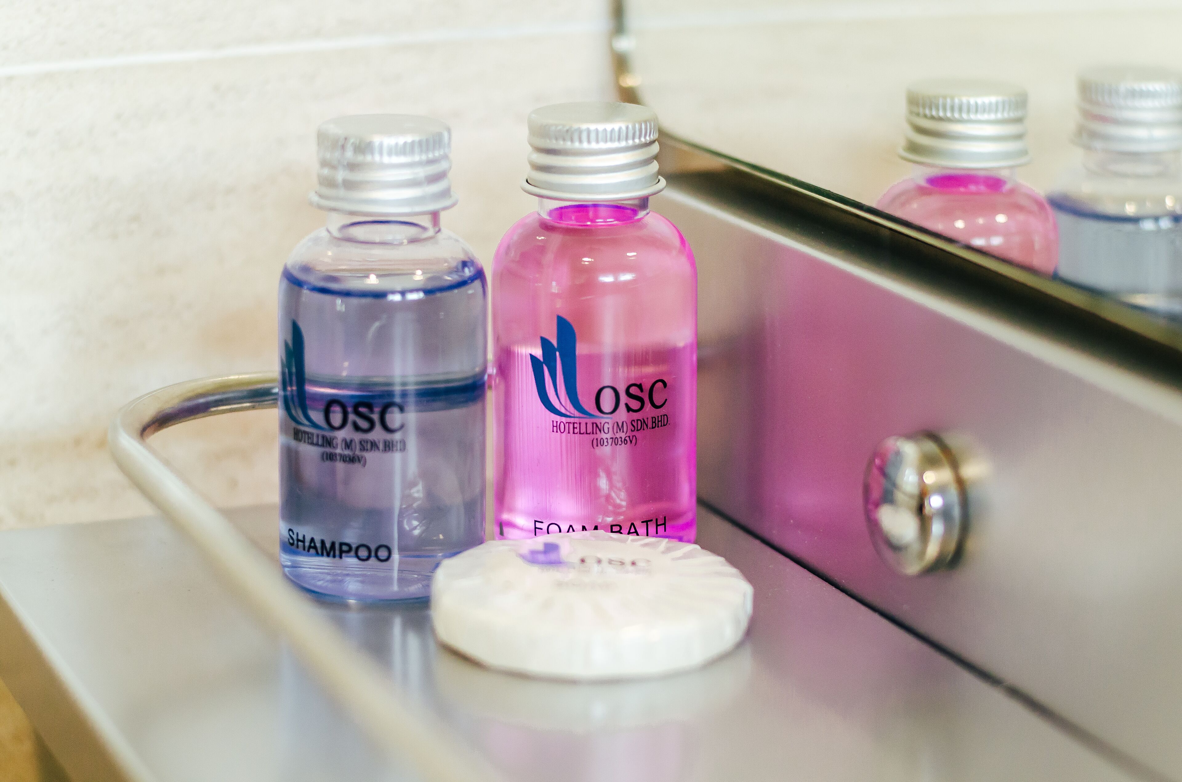 A bathroom counter with two bottles of shampoo and a bottle of foam bath.