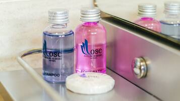 A bathroom counter with two bottles of shampoo and a bottle of foam bath.