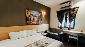 A hotel room with a large bed, a desk, a chair, a painting on the wall, and a window with curtains. - Kertih Damansara Inn (Kerteh)