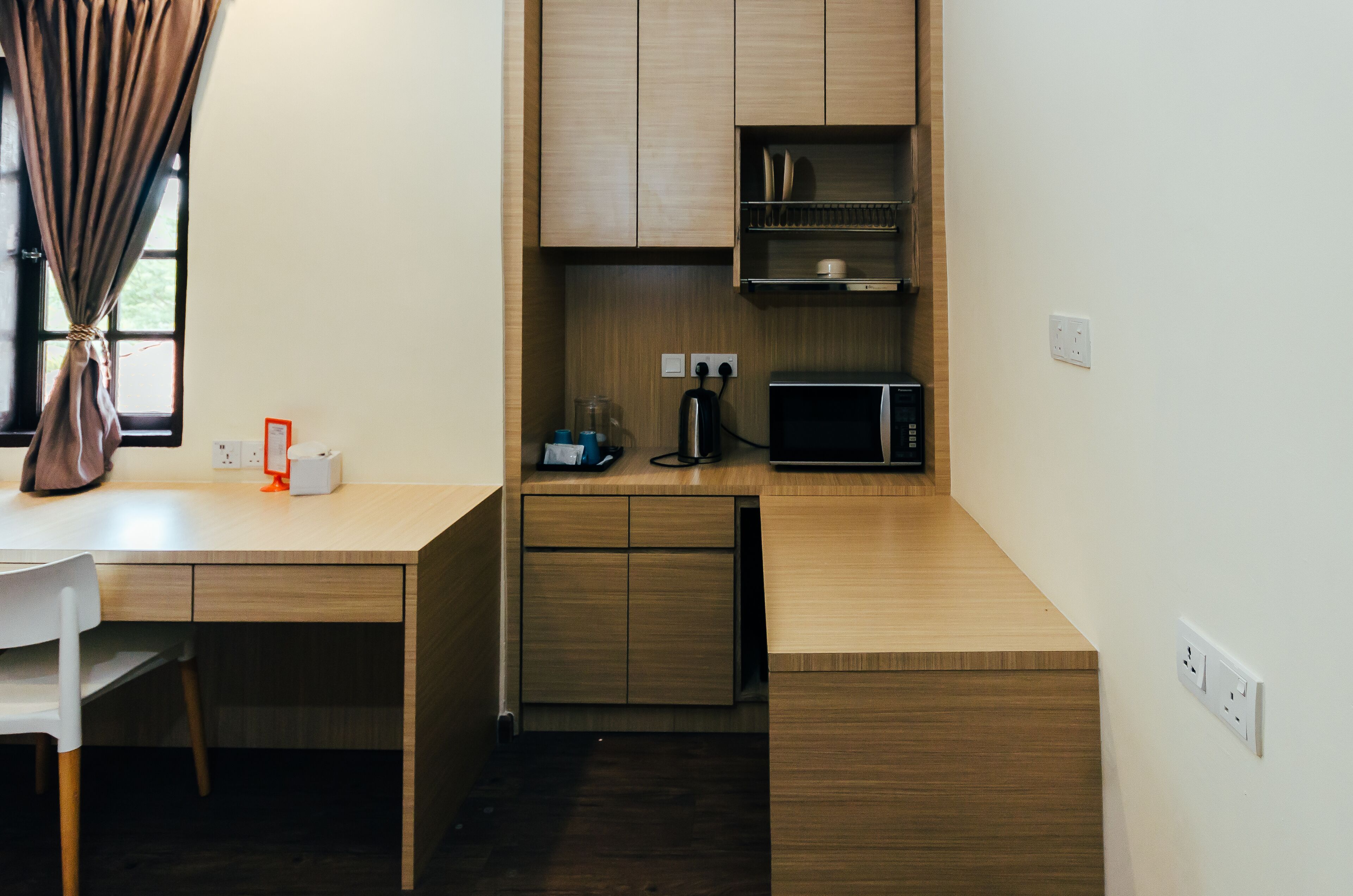 A compact kitchen with wooden cabinets, a microwave, and a coffee maker.