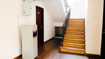 A hallway with a wooden staircase, a white refrigerator, and a door.