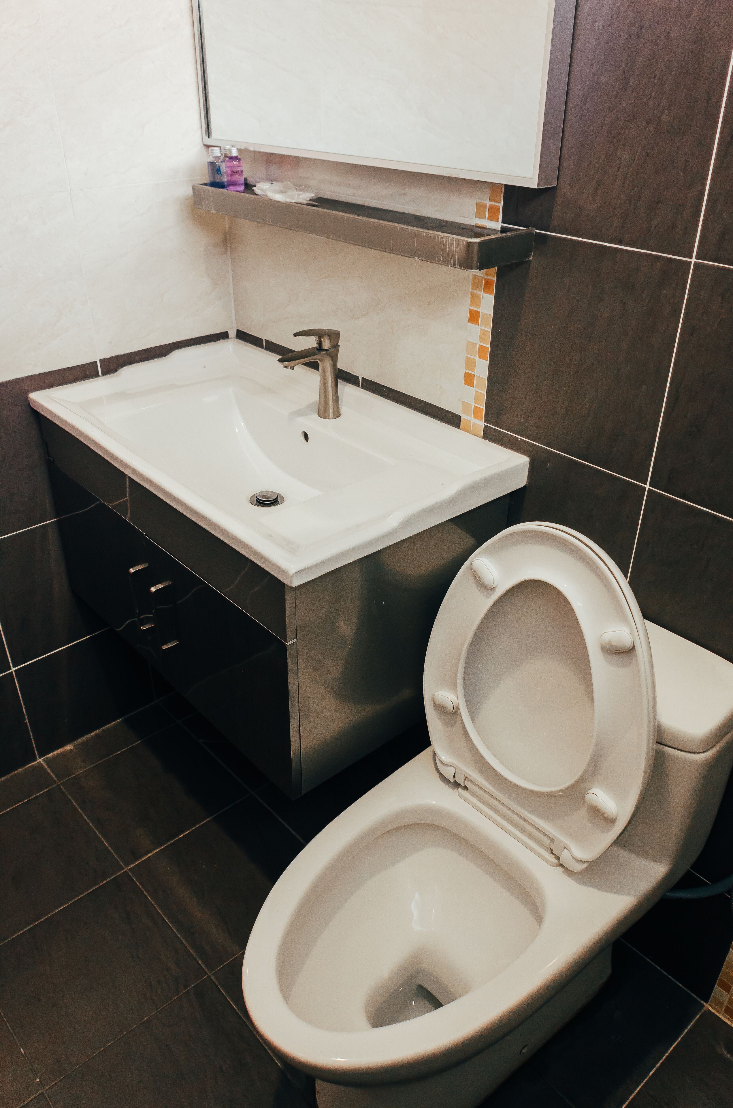 Un baño con lavamanos blanco, inodoro y espejo sobre el lavamanos.