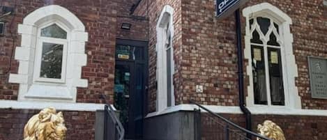 Un edificio de ladrillo con un letrero que dice 'OPEN' y una estatua de león en la entrada.