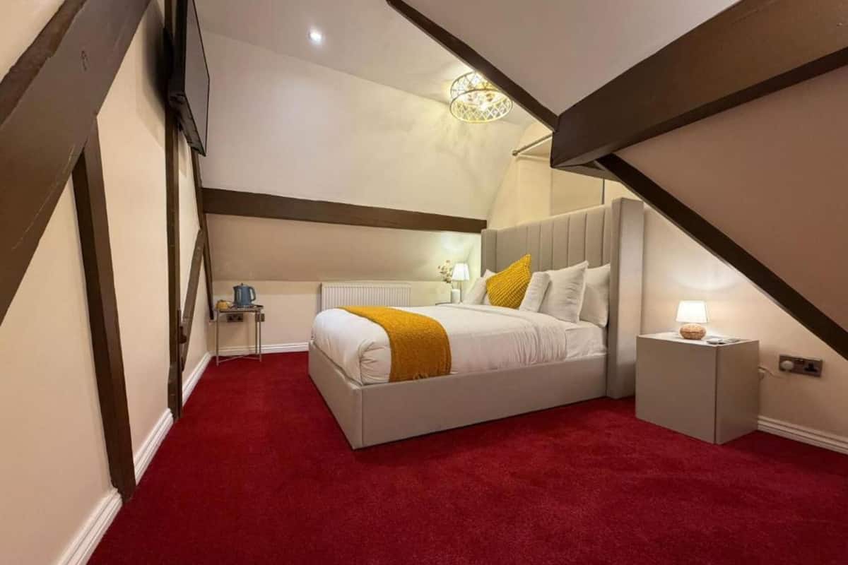Un dormitorio con cama, mesita de noche, lámpara, radiador y candelabro.