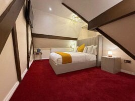 Un dormitorio con cama, mesita de noche, lámpara, radiador y candelabro.
