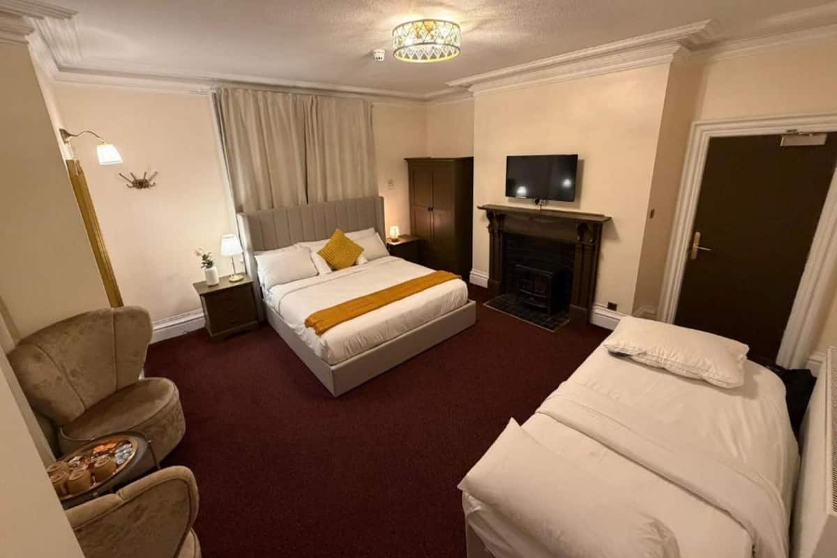Una habitación de hotel con una cama grande, televisión, chimenea y zona de estar.