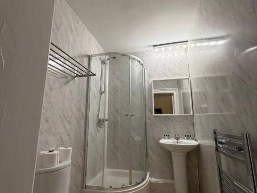 Een badkamer met toilet, douchecabine, wastafel en spiegel.