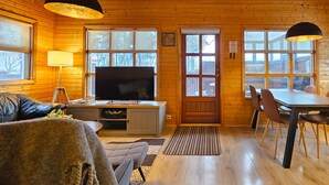 Un interior acogedor de cabaña con detalles de madera, un comedor, un televisor y un sofá.