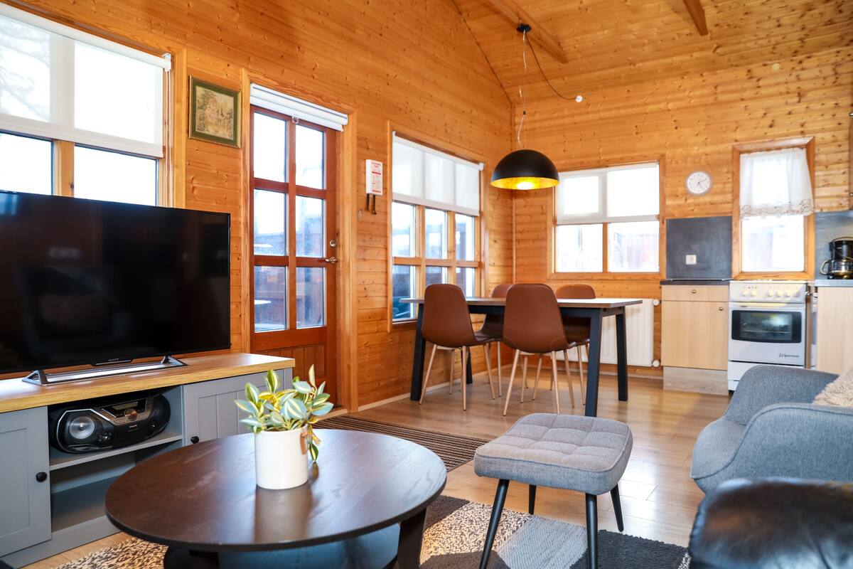 Ein gemütliches Blockhaussinnere mit Fernseher, Essbereich und Küche.