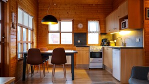 Interior de una cabaña de madera con comedor, cocina y zona de estar.