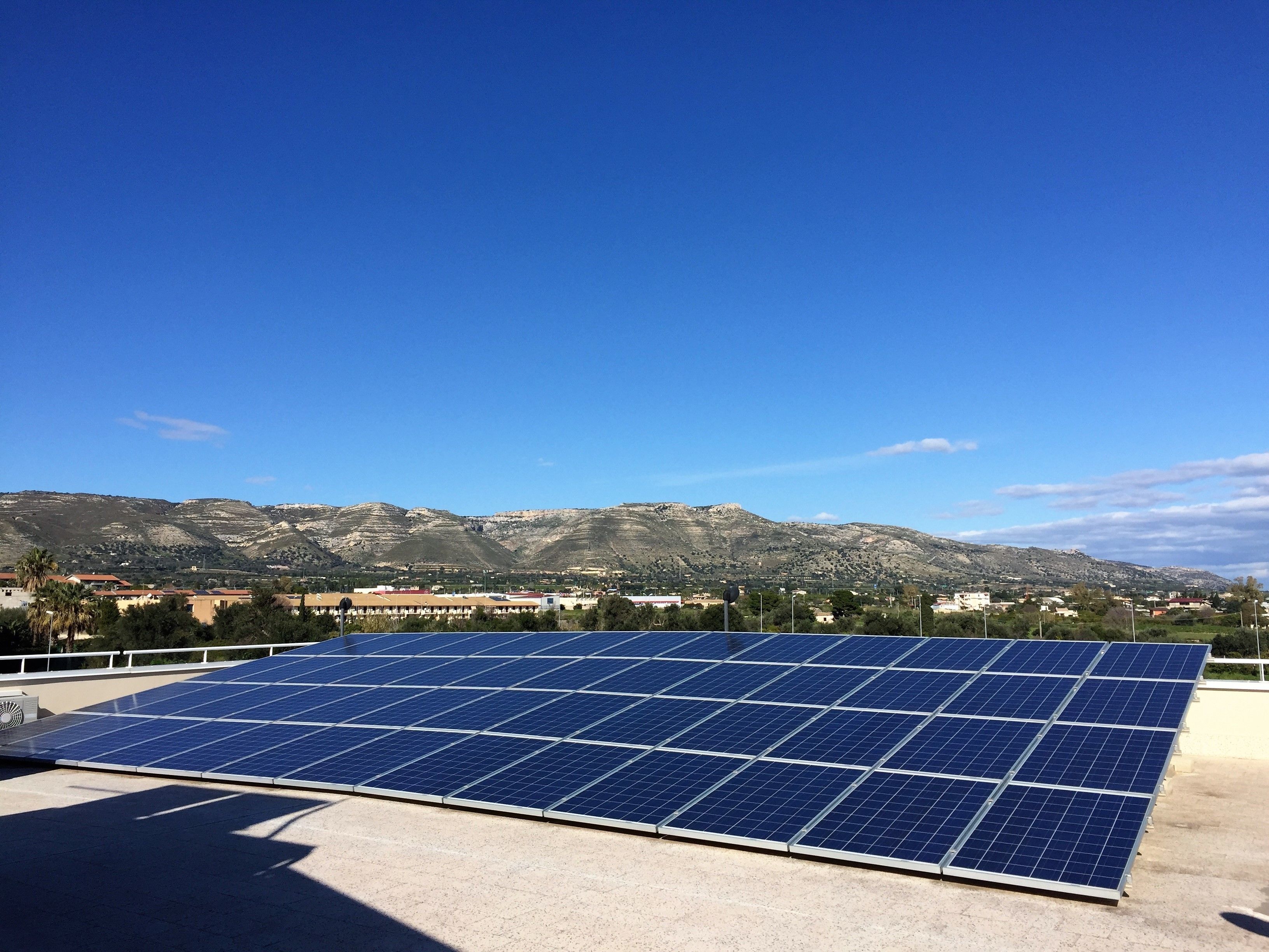 Een dak met zonnepanelen en een uitzicht op bergen in de verte.