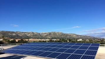 Een dak met zonnepanelen en een uitzicht op bergen in de verte.