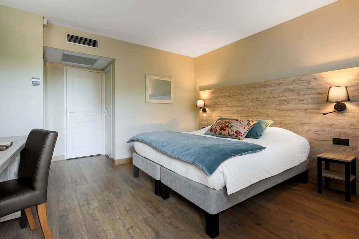 Una camera da letto con un letto, un comodino, una lampada e una scrivania con una sedia.