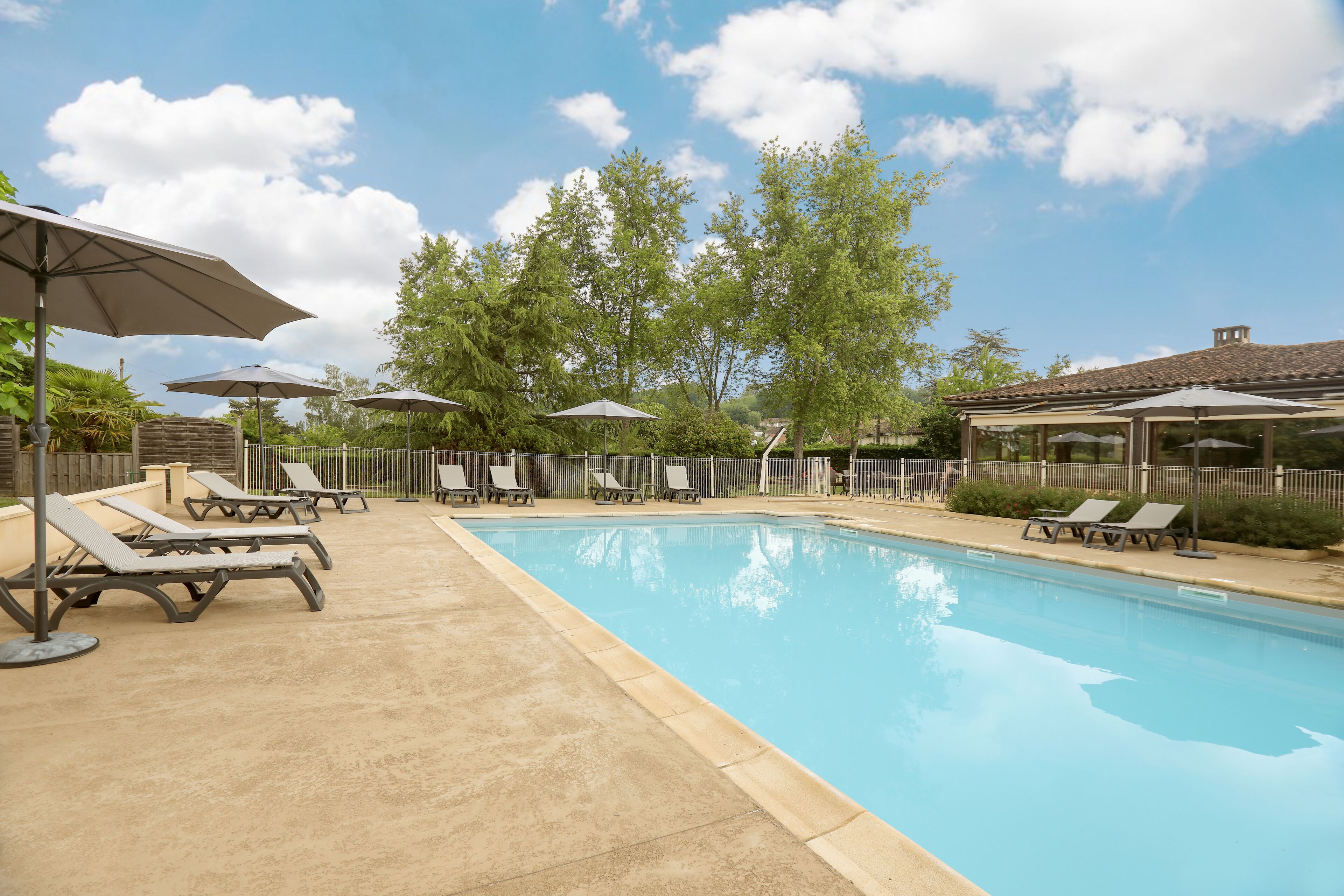 A swimming pool with lounge chairs and umbrellas.