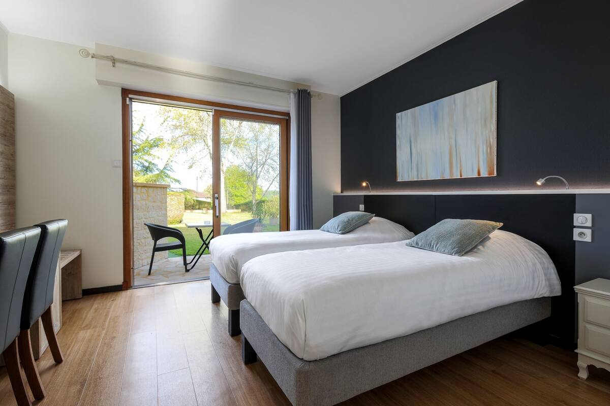 Una camera da letto con due letti, una scrivania e vista sull'esterno.