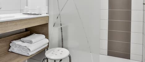 A modern bathroom with a glass shower enclosure, a wooden vanity, and a white sink.