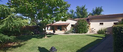 A residential property with a well-maintained lawn, a patio with outdoor furniture, and a pathway leading to the entrance.